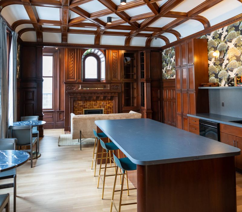 Elegant kitchen and lounge with wood paneling, island seating, marble tables, and decorative wallpaper.